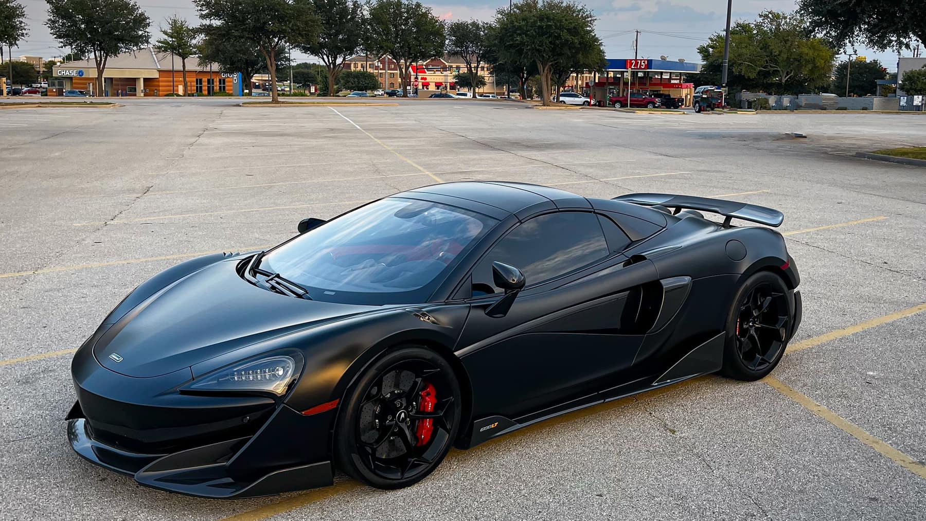 A matte black supercar parked alone in an empty lot at golden hour