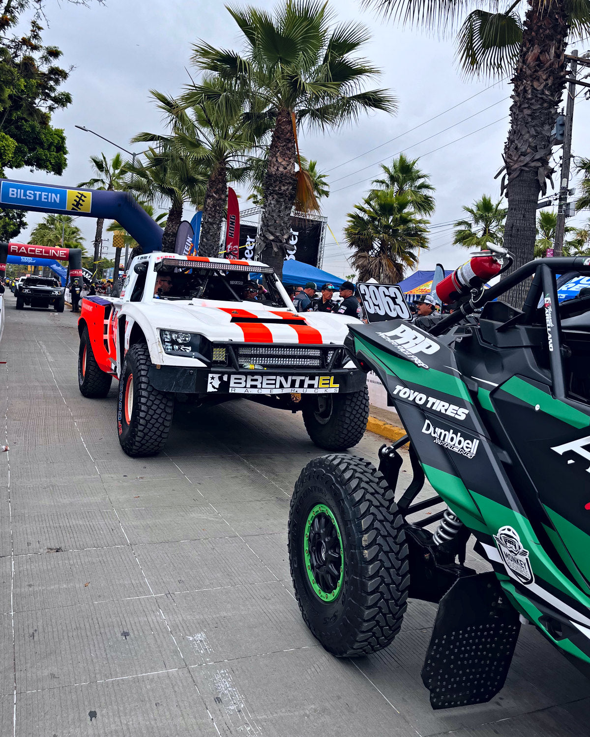 A desert race truck and an off-road buggy in the paddock at an off-road event